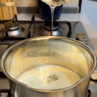 Una persona sta versando del liquido in una pentola sul fornello.