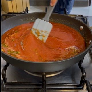 Una persona sta mescolando una padella di salsa con una spatola