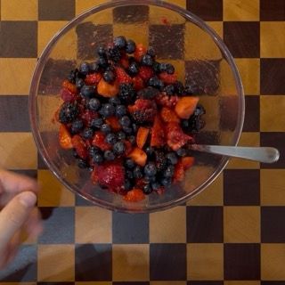 I frutti rossi mescolati a freddo per mantenere i succhi perfetti nel crumble ai mirtilli e lamponi.