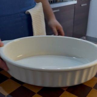 Versamento dei frutti di bosco conditi in una pirofila rettangolare per il goloso crumble ricetta originale.