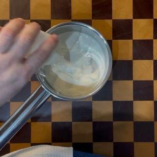 Riscaldamento della prima dose di panna con zucchero e vaniglia per guarnire il caldo crumble ai mirtilli.