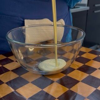 Versamento del cioccolato bianco fuso in una ciotola calda per accompagnare il crumble ricetta originale.
