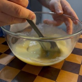 Aggiunta della seconda parte di panna calda nell'emulsione di cioccolato per la ricca ganache di finitura.