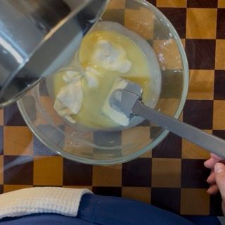 Ultimo versamento di panna calda e mescolamento per la crema di accompagnamento del crumble ai frutti rossi.