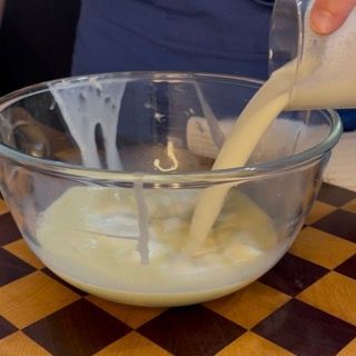 Aggiunta della panna liquida fredda al composto di cioccolato bianco per servire il crumble ai frutti rossi.
