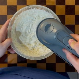 Montatura della ganache al cioccolato bianco con fruste elettriche per guarnire il crumble dorato e tiepido.