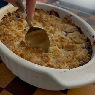 Sporzionamento con cucchiaio del crumble ai frutti di bosco ricetta ancora tiepido direttamente dalla pirofila.