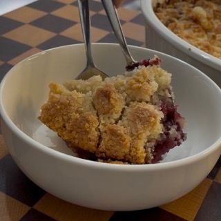 Creazione di una elegante quenelle di ganache montata per decorare il piatto di crumble ai mirtilli e lamponi.