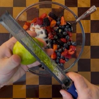 Aggiunta di zucchero, succo e scorza di limone ai frutti rossi per la profumata crumble ricetta originale.