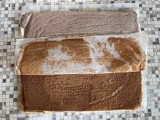 Un pezzo di torta al cioccolato è appoggiato su un tavolo piastrellato.