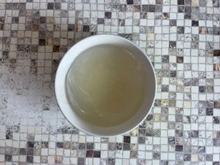 Una ciotola piena di liquido è appoggiata su un tavolo piastrellato.