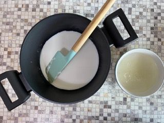 Una padella con una spatola dentro e una ciotola di liquido accanto.