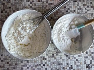 Due ciotole di panna montata con una frusta e una spatola su un tavolo.