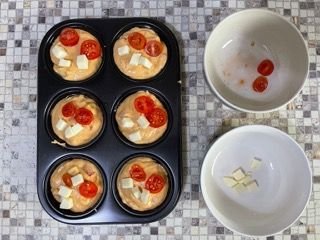 Uno stampo per muffin riempito con muffin con pomodori e formaggio.
