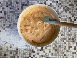 Una ciotola di cibo con una spatola dentro su un tavolo.