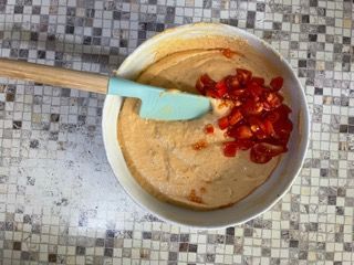 Una ciotola di cibo con dentro dei pomodori e una spatola.