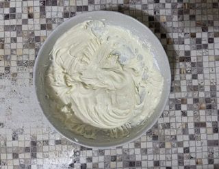 Una ciotola di panna montata è appoggiata su un bancone piastrellato.