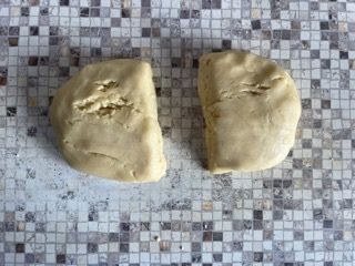 Due pezzi di pasta sono appoggiati su un bancone piastrellato.