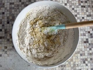 Una ciotola di farina e burro viene mescolata con una spatola.