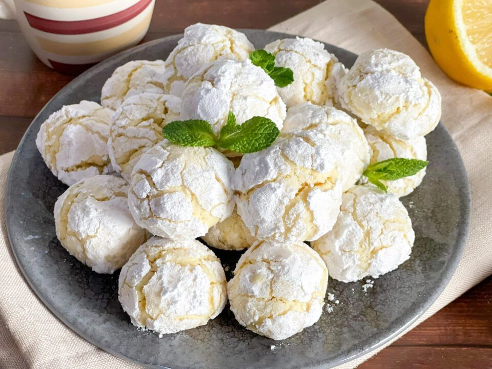 Un piatto di biscotti con zucchero a velo e foglie di menta su un tavolo.
