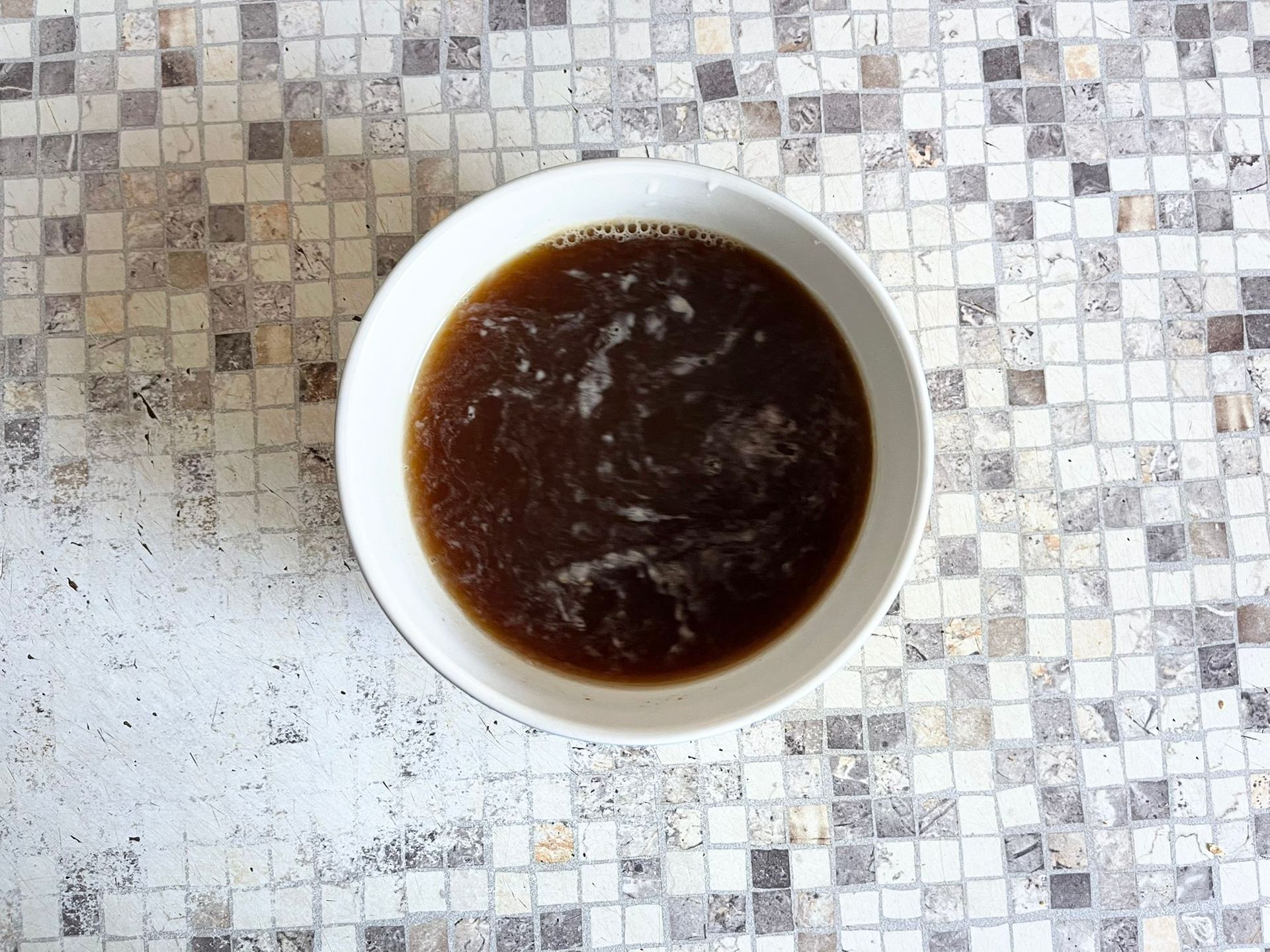 Una ciotola di zuppa è appoggiata su un tavolo a scacchi.