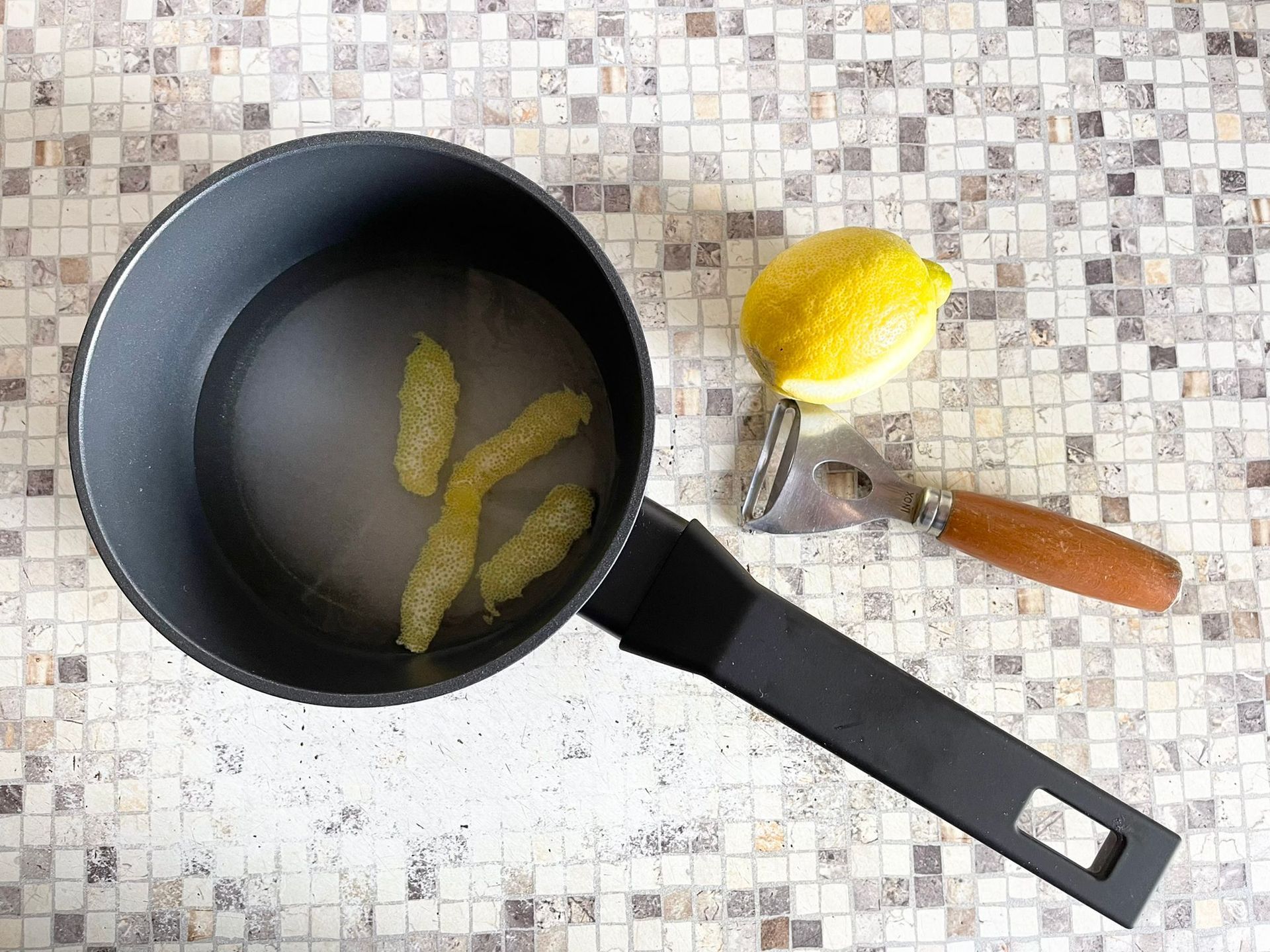 Una pentola di liquido accanto a un limone e una forchetta su un tavolo.