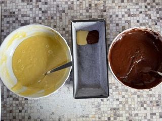 Due ciotole di pastella e due ciotole di salsa al cioccolato su un tavolo.