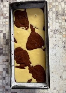 Uno stampo da plumcake riempito con pastella marrone e bianca