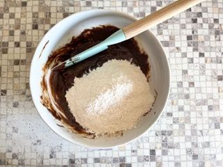 Una ciotola con cioccolato e farina e una spatola dentro.