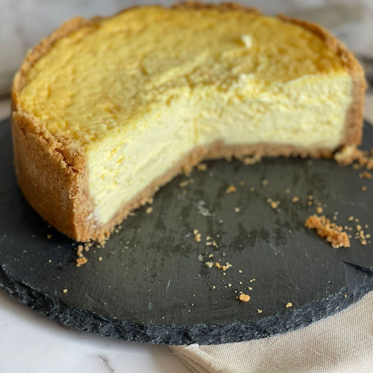 Una cheesecake con una fetta tagliata è su un tagliere.