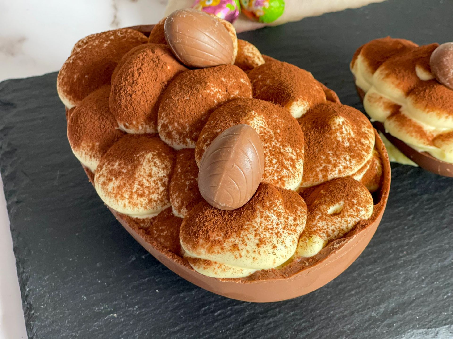 Un uovo di Pasqua al cioccolato ripieno di tiramisù e uova di cioccolato