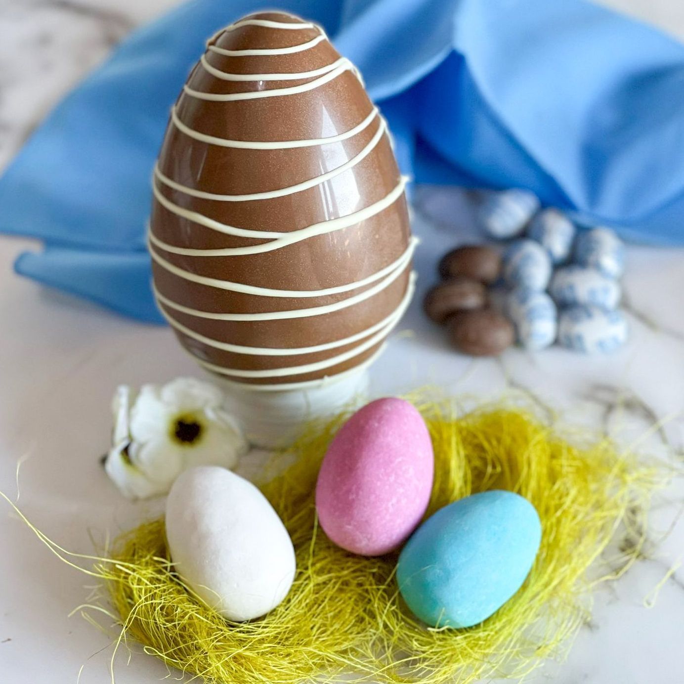 Un uovo di Pasqua ricoperto di cioccolato appoggiato su un nido di uova