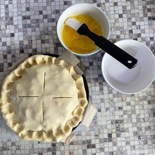 Una torta appoggiata su un tavolo accanto a una ciotola di uova