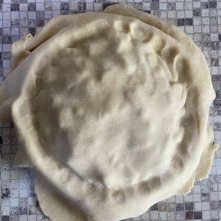 Una base per pizza è appoggiata su un piano piastrellato.