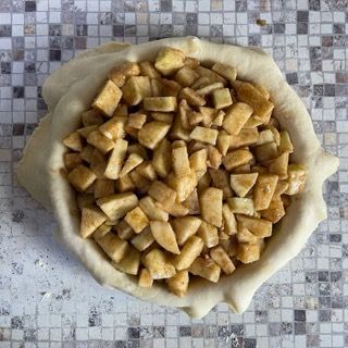 Una crosta di torta ripiena di mele tritate su un tavolo
