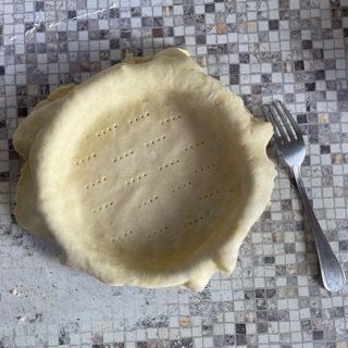 Una crosta di torta è appoggiata su un tavolo accanto a una forchetta