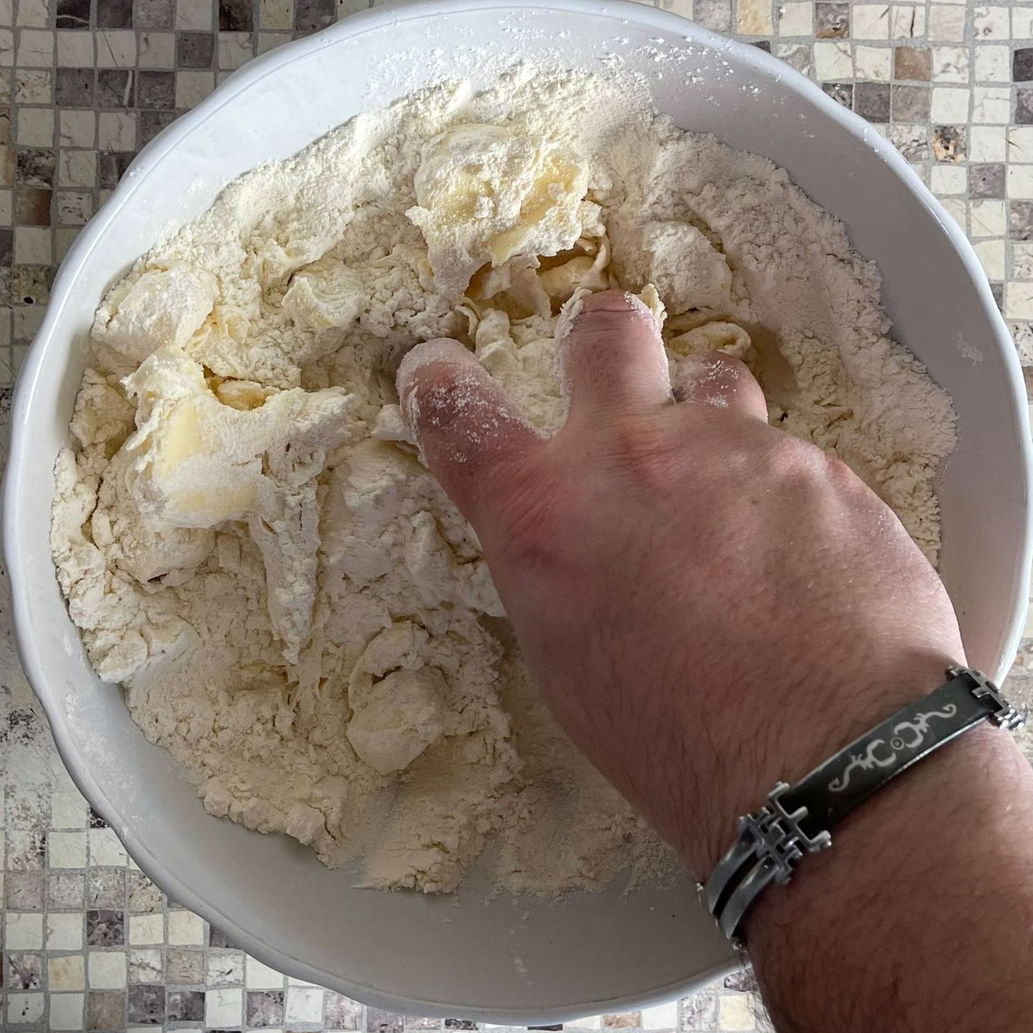 Una persona che indossa un braccialetto sta mescolando gli ingredienti in una ciotola.