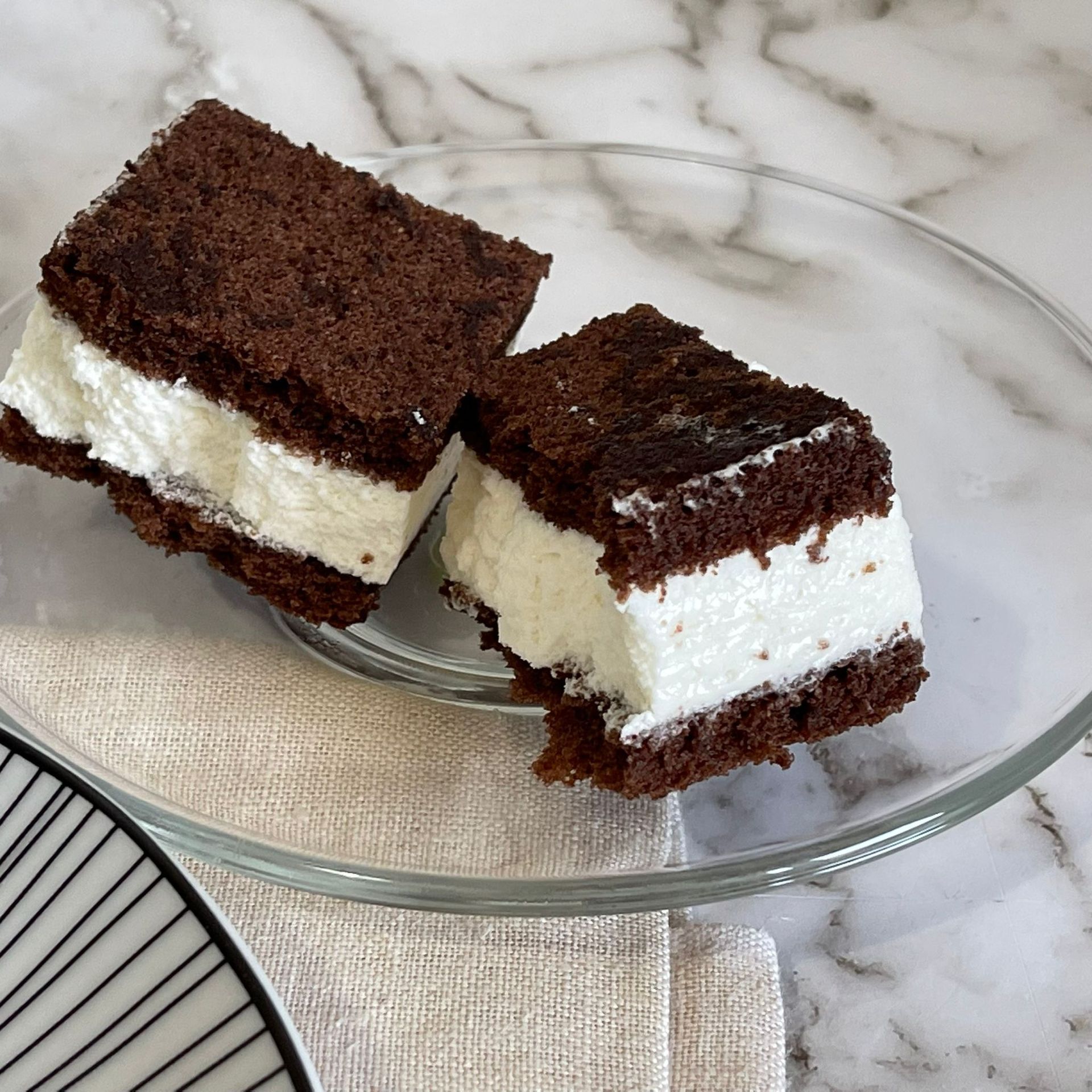 Due pezzi di torta al cioccolato con glassa bianca su un piatto di vetro