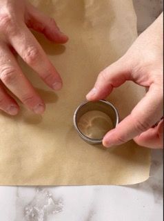 Una persona tiene in mano un anello di metallo su un pezzo di carta marrone.