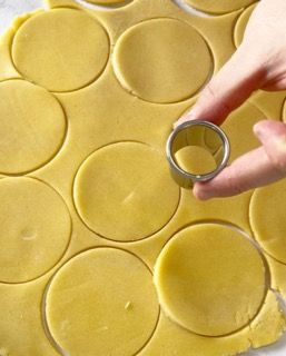 Una persona sta tagliando dei cerchi dall'impasto con un tagliabiscotti