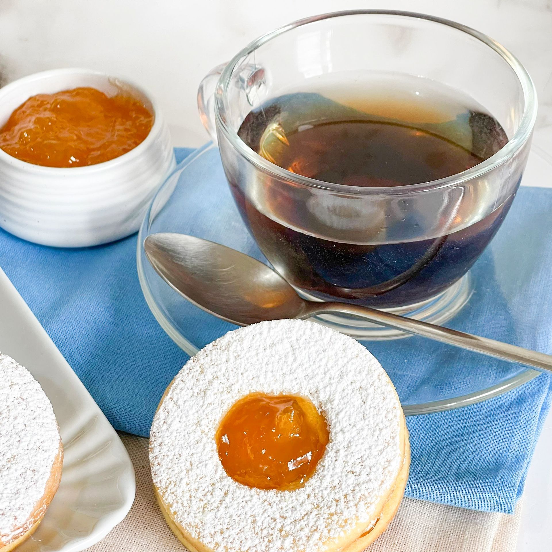 Una tazza di caffè accanto a un biscotto con la marmellata sopra
