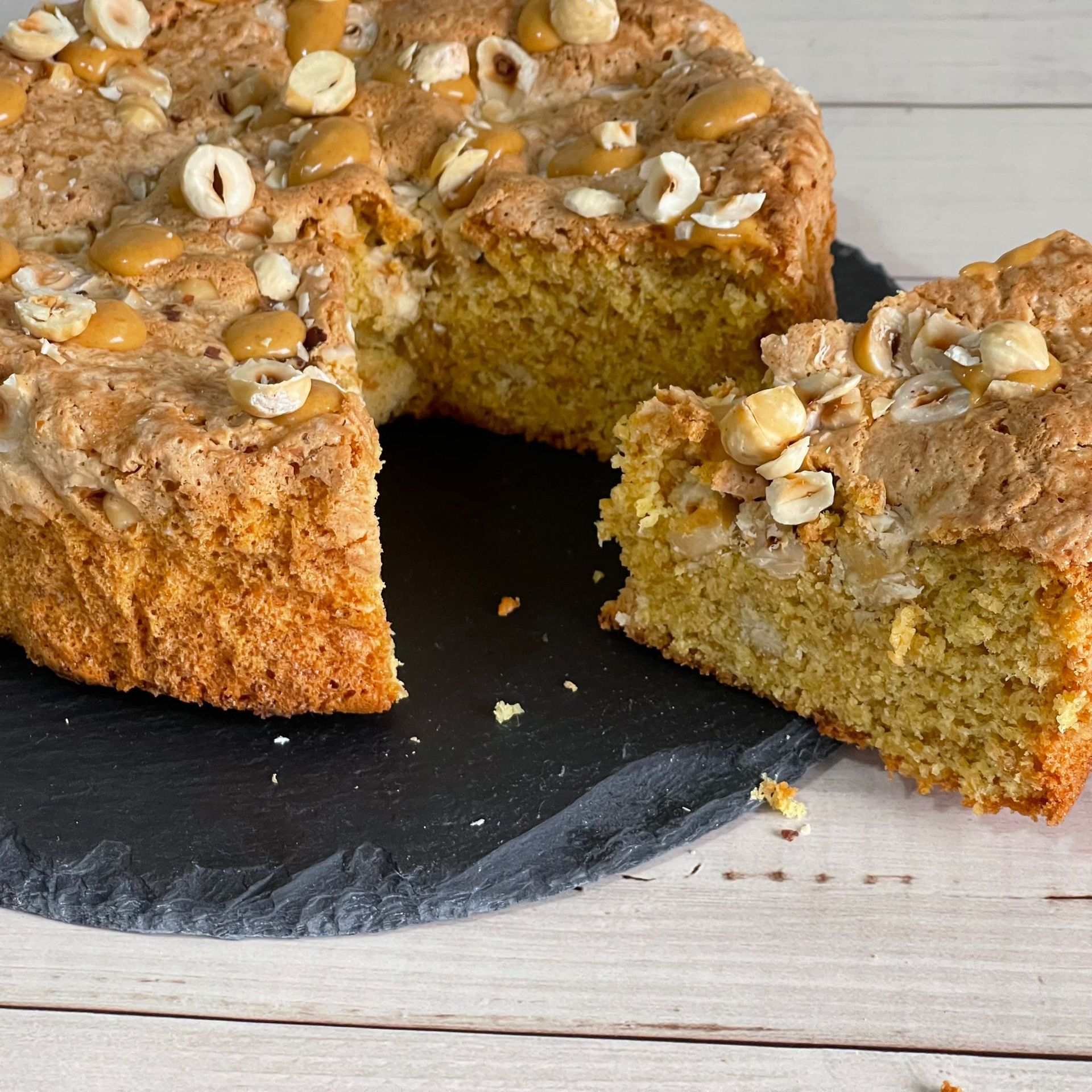Una torta da cui è stata staccata una fetta è su un piatto nero.