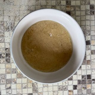Una ciotola di zuppa è appoggiata su un piano di lavoro piastrellato