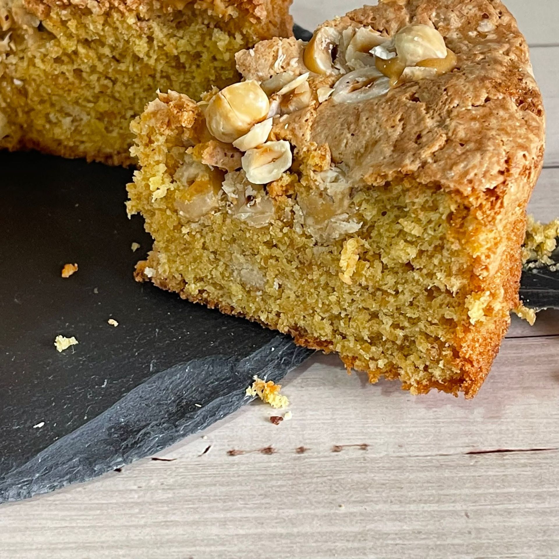 Una fetta di torta con sopra delle noci è appoggiata su un tavolo.