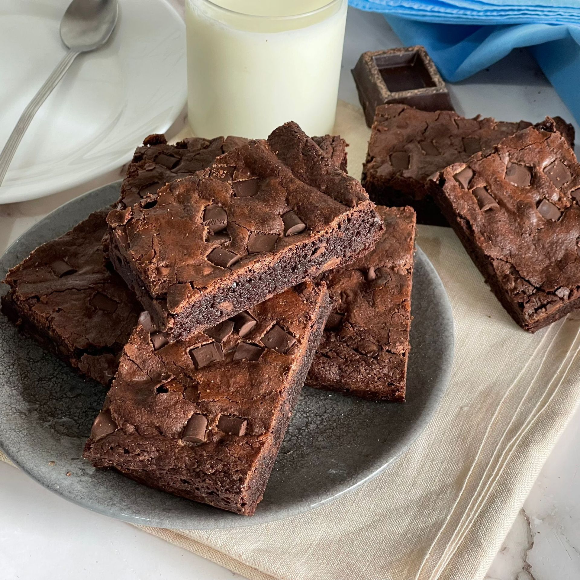 Un piatto di brownies e un bicchiere di latte su un tavolo.
