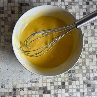 Una ciotola di liquido giallo con una frusta dentro