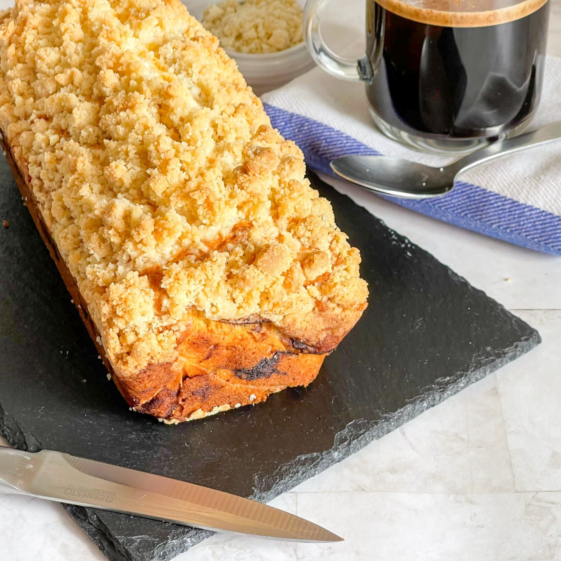 Una pagnotta di pane è appoggiata su un tagliere accanto a una tazza di caffè