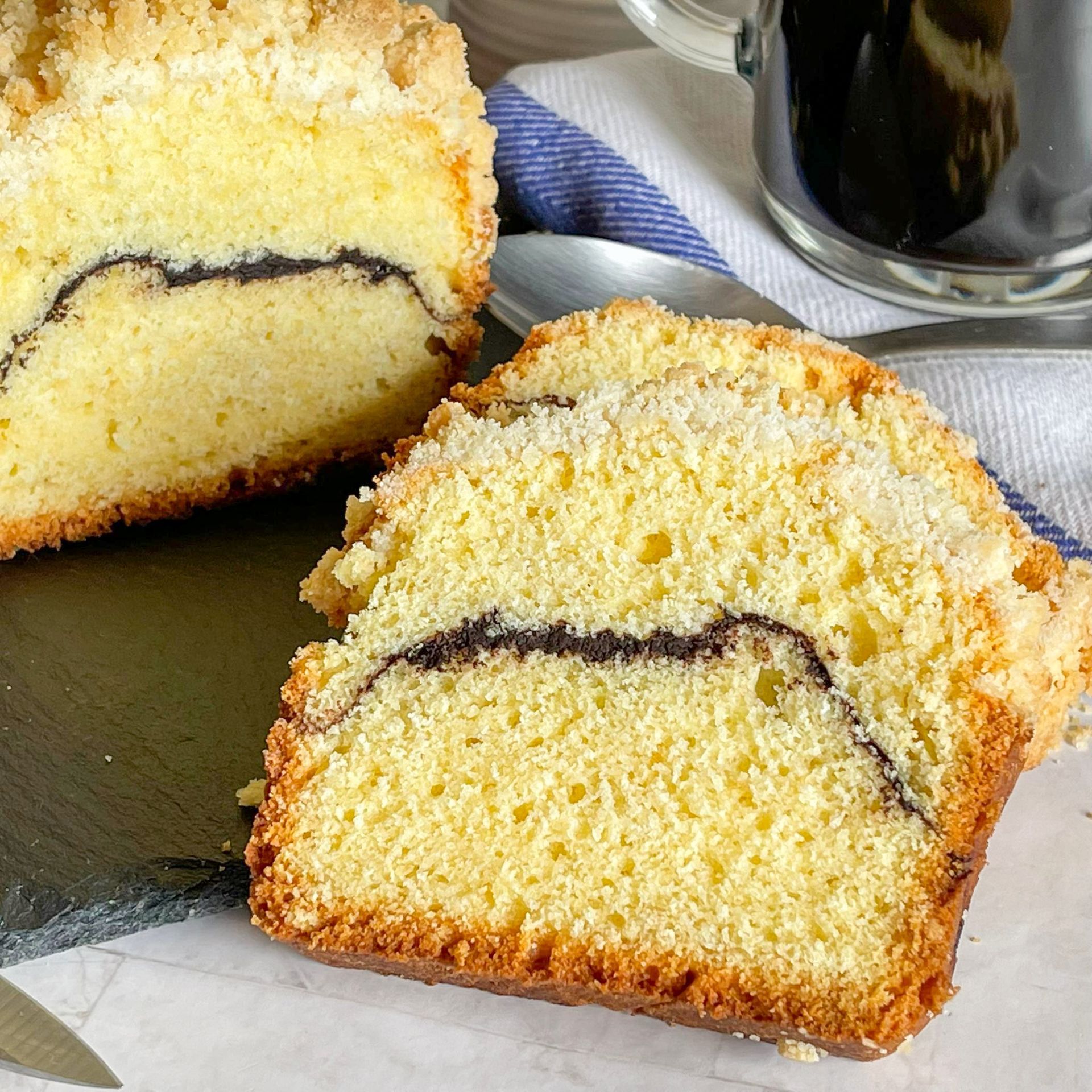 Due fette di torta sono appoggiate su un tavolo accanto a una tazza di caffè.
