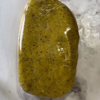 Un pezzo di pasta gialla è avvolto nella plastica e appoggiato su un tavolo.