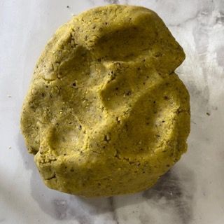 Un pezzo di pasta gialla è appoggiato su un tavolo.